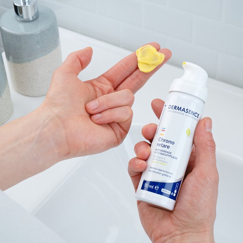 Gele vitamine-C nachtcrème van Dermasence op vingertop, klaar om op het gezicht aan te brengen.