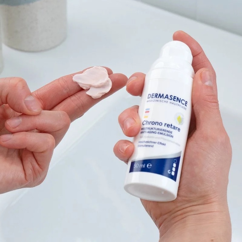 Lichtroze emulsie op twee vingers met de flacon in de andere hand gehouden