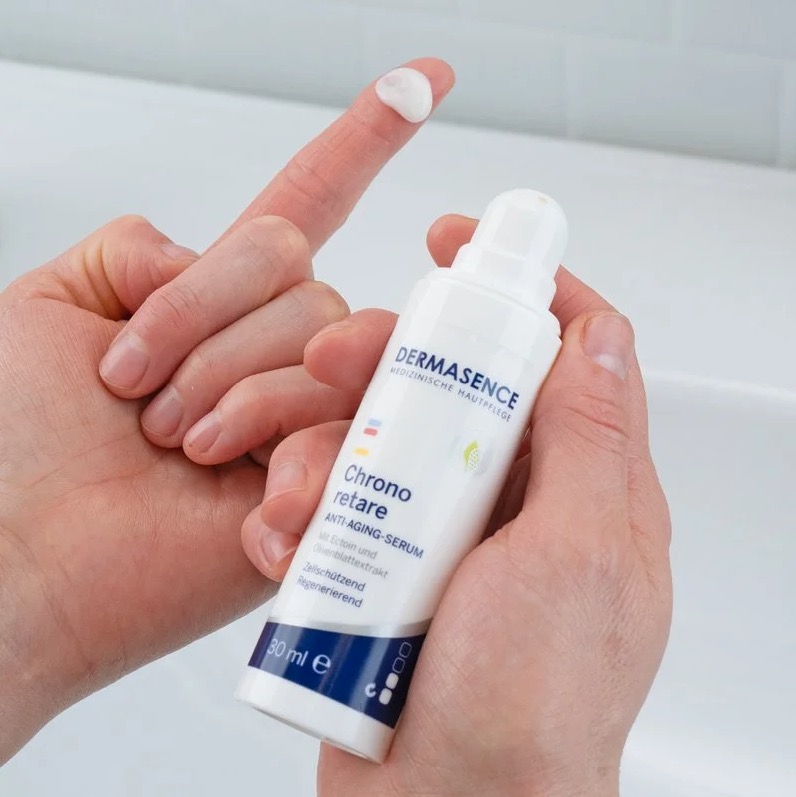 Wit dermasence serum op een vinger met de flacon in andere hand