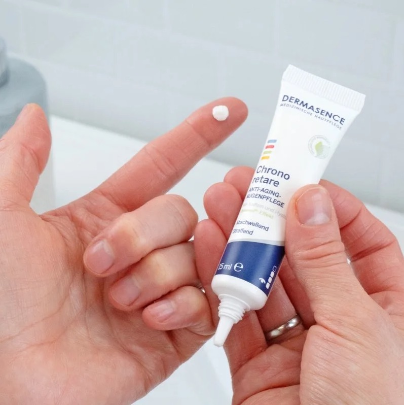Dotje Dermasence oogcreme op een vinger met de tube in de andere hand