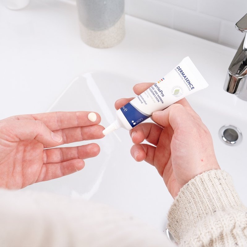 DERMASENCE BarrioPro wond- en littekenverzorging emulsie wordt op een vingertop aangebracht boven een wastafel.